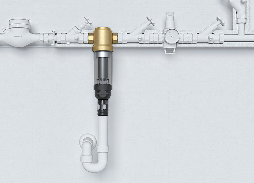 An das Hauptrohr der Trinkwasserleitung fügt sich ein längliches, hier durchsichtiges Rohr aus Kunststoff an, das in einem Abflussrohr endet