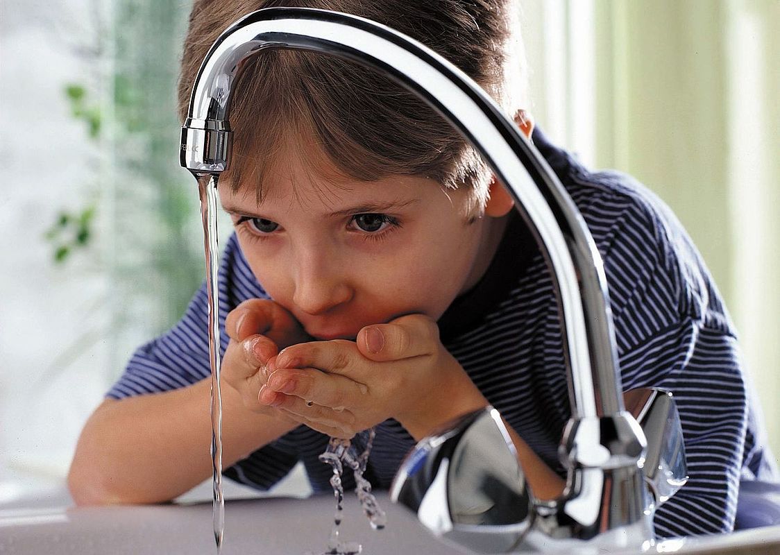 Junge trinkt Wasser am Waschbecken