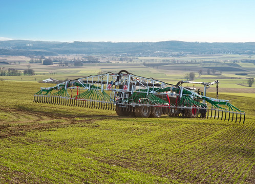 Traktor trägt Gülle mit einem Schleppschlauchsystem auf dem Feld aus.