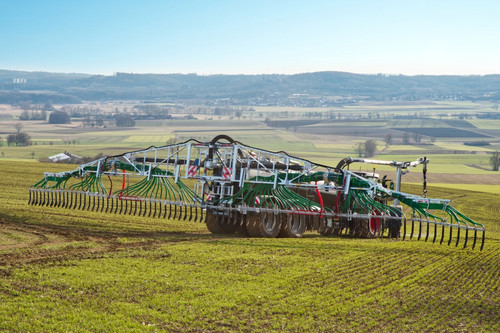 Traktor trägt Gülle mit einem Schleppschlauchsystem auf dem Feld aus.