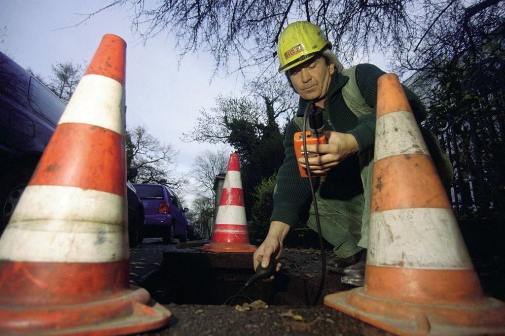 Mann prüft Gaskonzentration einer Gasleitung im Straßenbereich 