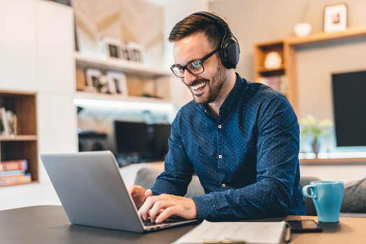 Mann mit Kopfhörern arbeitet am Laptop