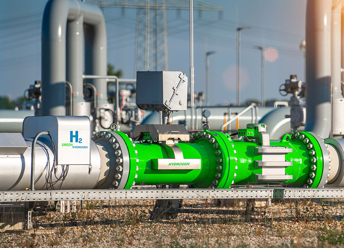 Ein mächtiges, im Freien liegendes, teils silbernes, teils grünes Rohr mit "H2"-Aufschrift