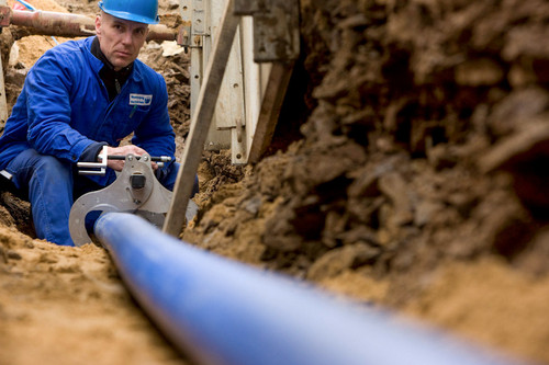 Mann arbeitet an im Erdreich verlegten Wasserleitungen