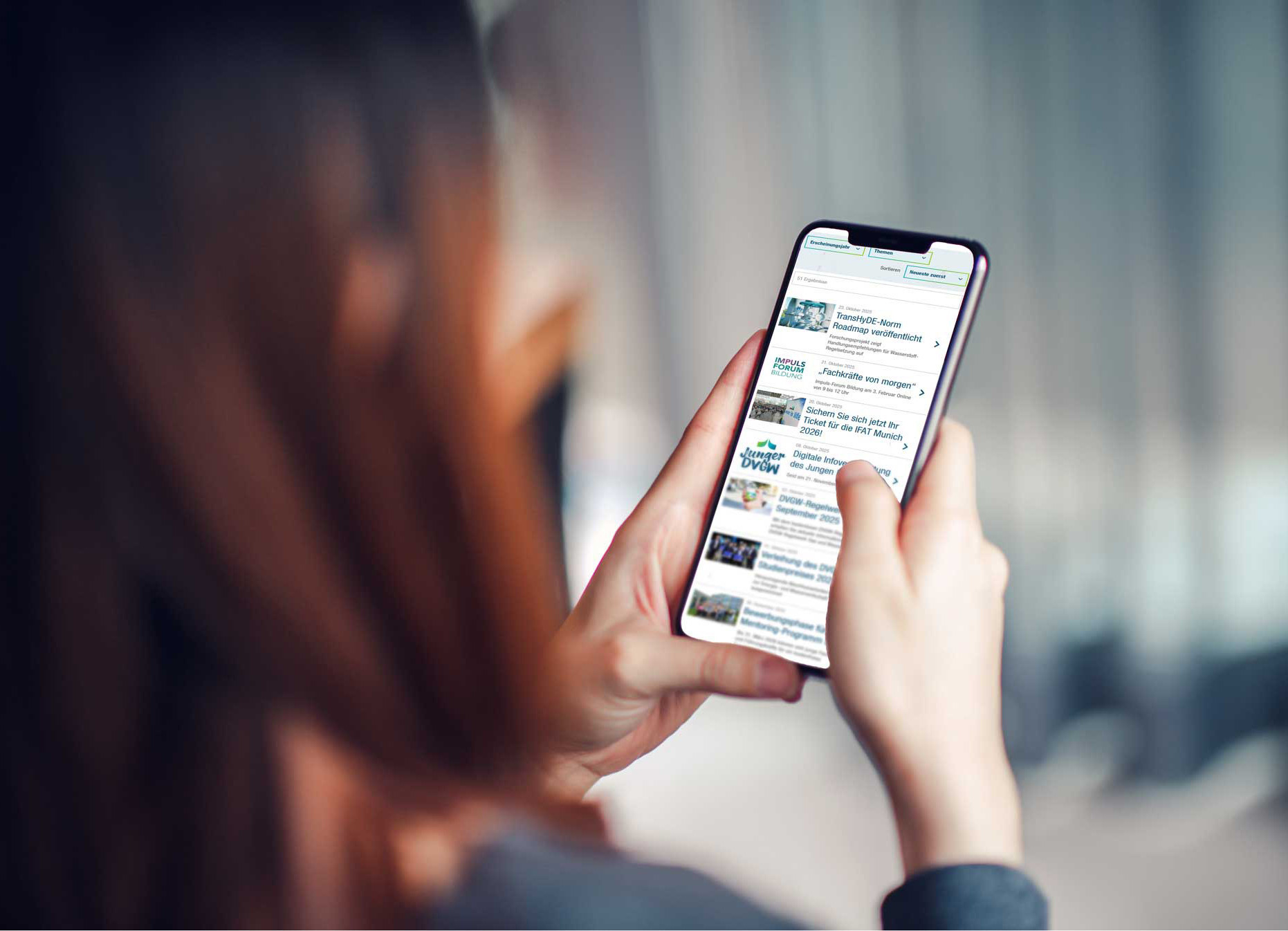 Blick über die Schulter einer Frau, die Presseinformationen auf ihrem Handy liest