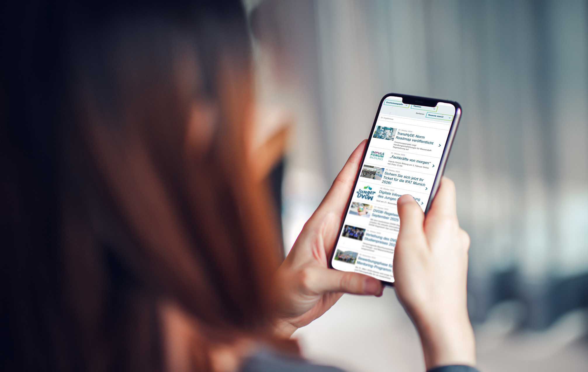 Blick über die Schulter einer Frau, die Presseinformationen auf ihrem Handy liest