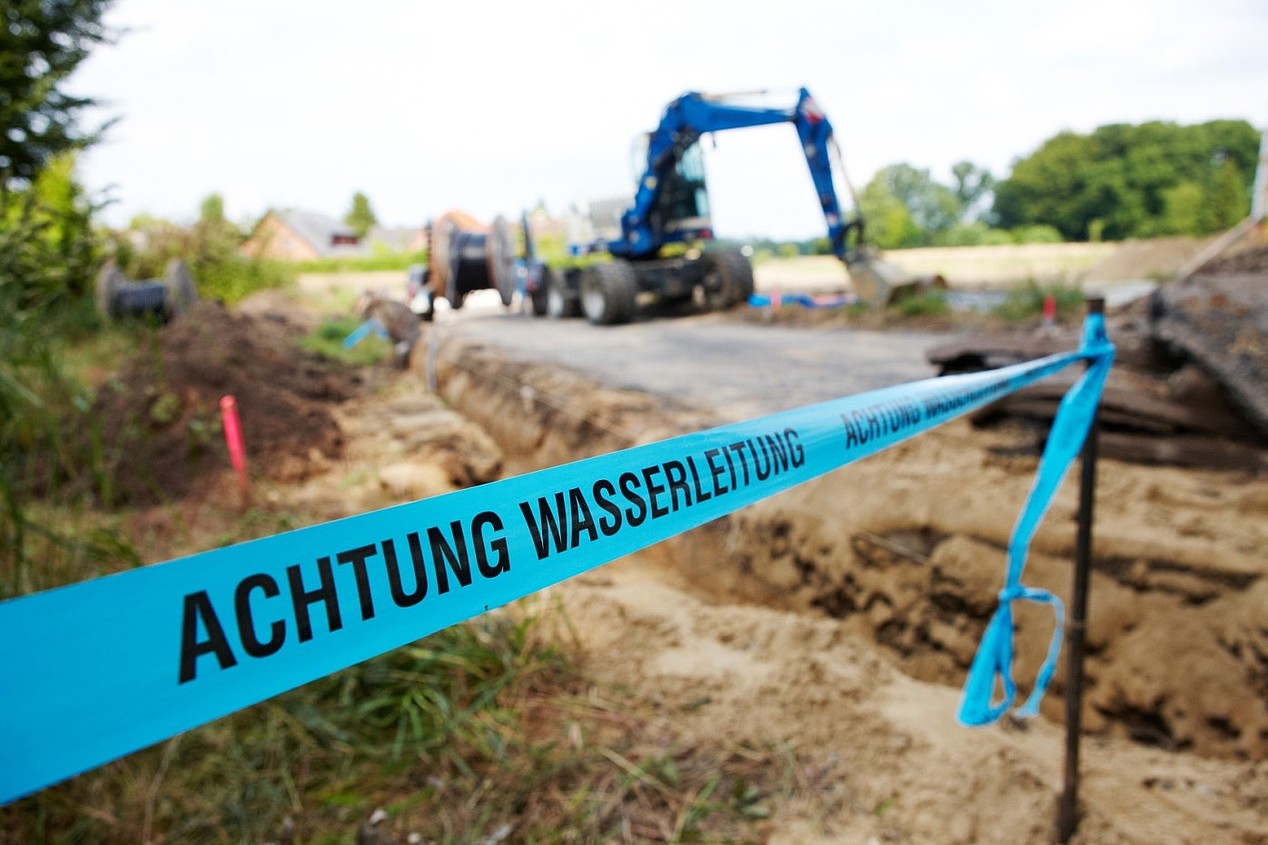 Blaues Absperrband zu einer Baustelle mit der Aufschrift: Achtung Wasserleitungen.