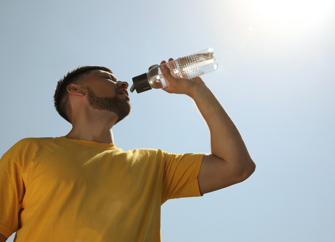Mann trinkt in der Mittagshitze aus einer Wasserflasche