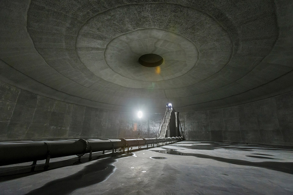 Leeres, riesiges Rund aus Beton mit einer Treppe nach oben ins Tageslicht