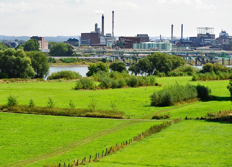 Industrieunternehmen an einem Fluss hinter grünen Feldern