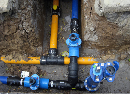 Gelbe Gas- und blaue Wasserrohre in einer Baustelle