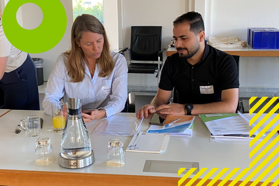 Eine Mentorin und ein Mentee sitzen am Tisch und besprechen sich
