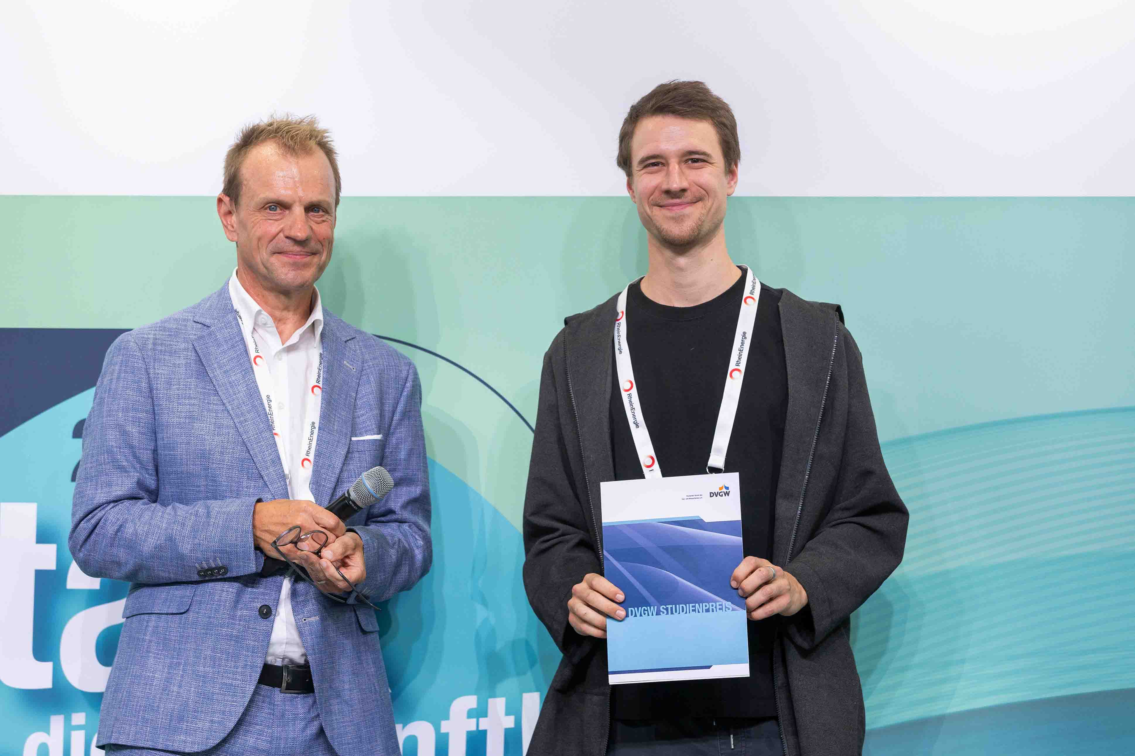 Christoph Jeromin, DVGW-Vizepräsident Wasser, und der Preisträger des Studienpreises Wasser stehen nebeneinander, Ullmann hält seine Urkunde vor den Bauch